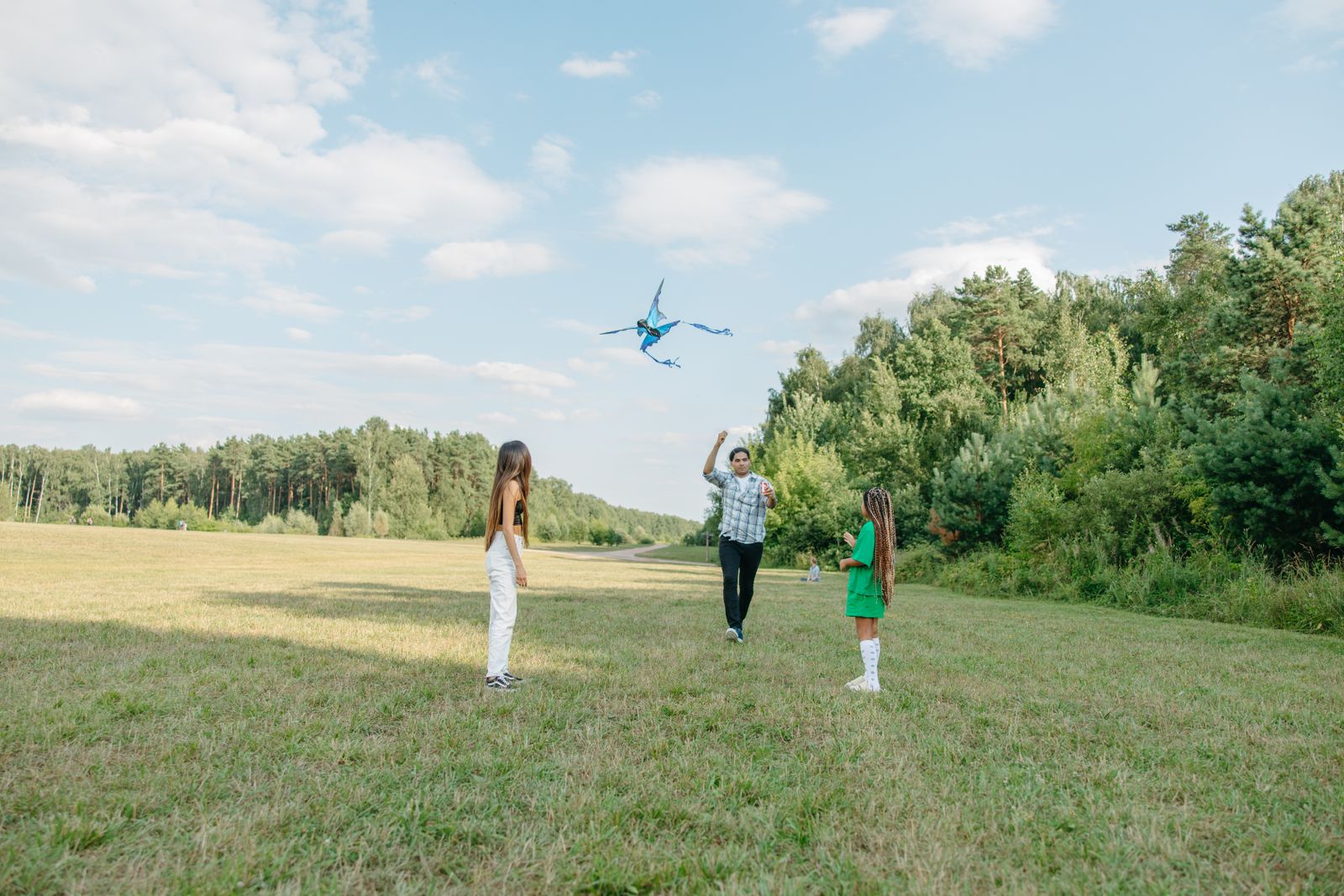Family flying a kite in a park on a summer day